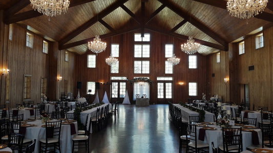 Elegant wedding reception hall with wooden beams and crystal chandeliers.