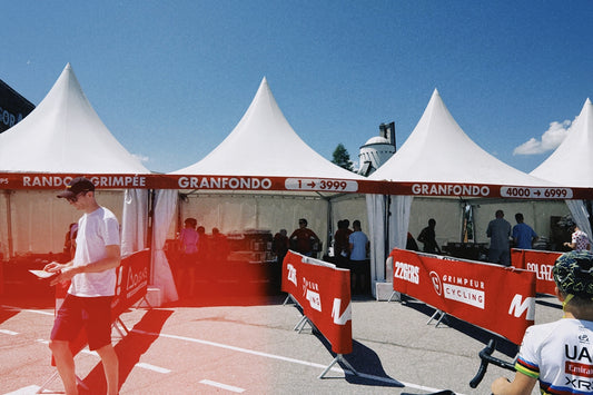 White tents and red grandfondo banners at outdoor event