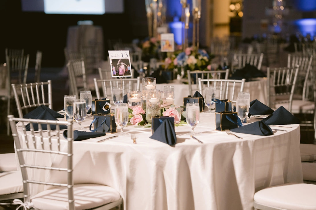 Event table with white tablecloth, silver chairs, and floral centerpiece.