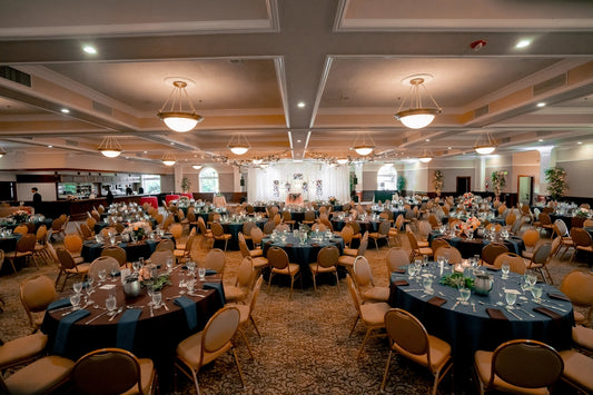 Elegant ballroom with numerous tables prepared for a formal event.