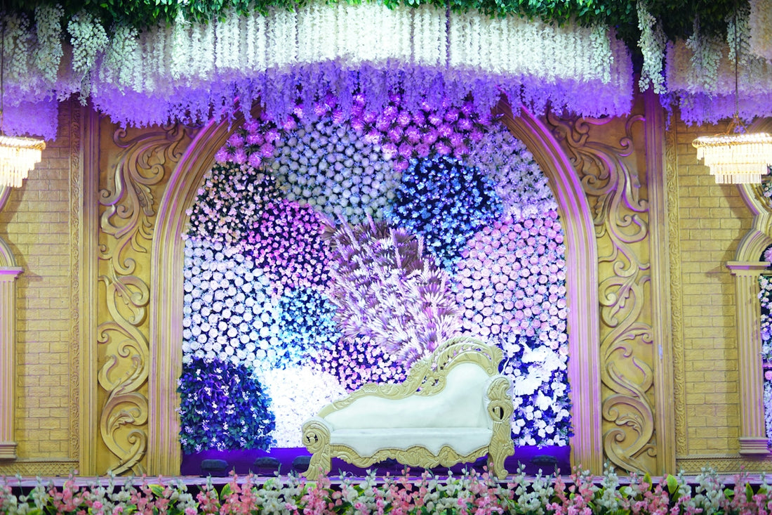 A white ornate chaise lounge in front of a floral wedding stage backdrop